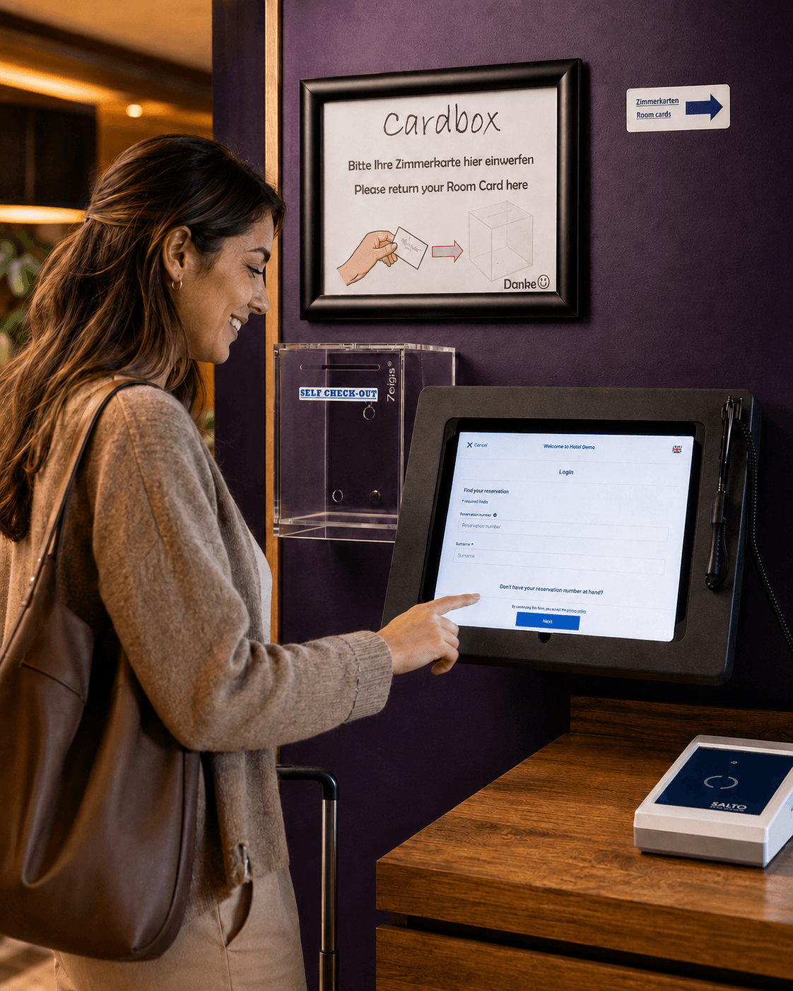 Eine Reisende mit Umhängetasche und Koffer checkt sich am Self-Check-in-Terminal des Hotels selbst ein und tippt auf den Touchscreen