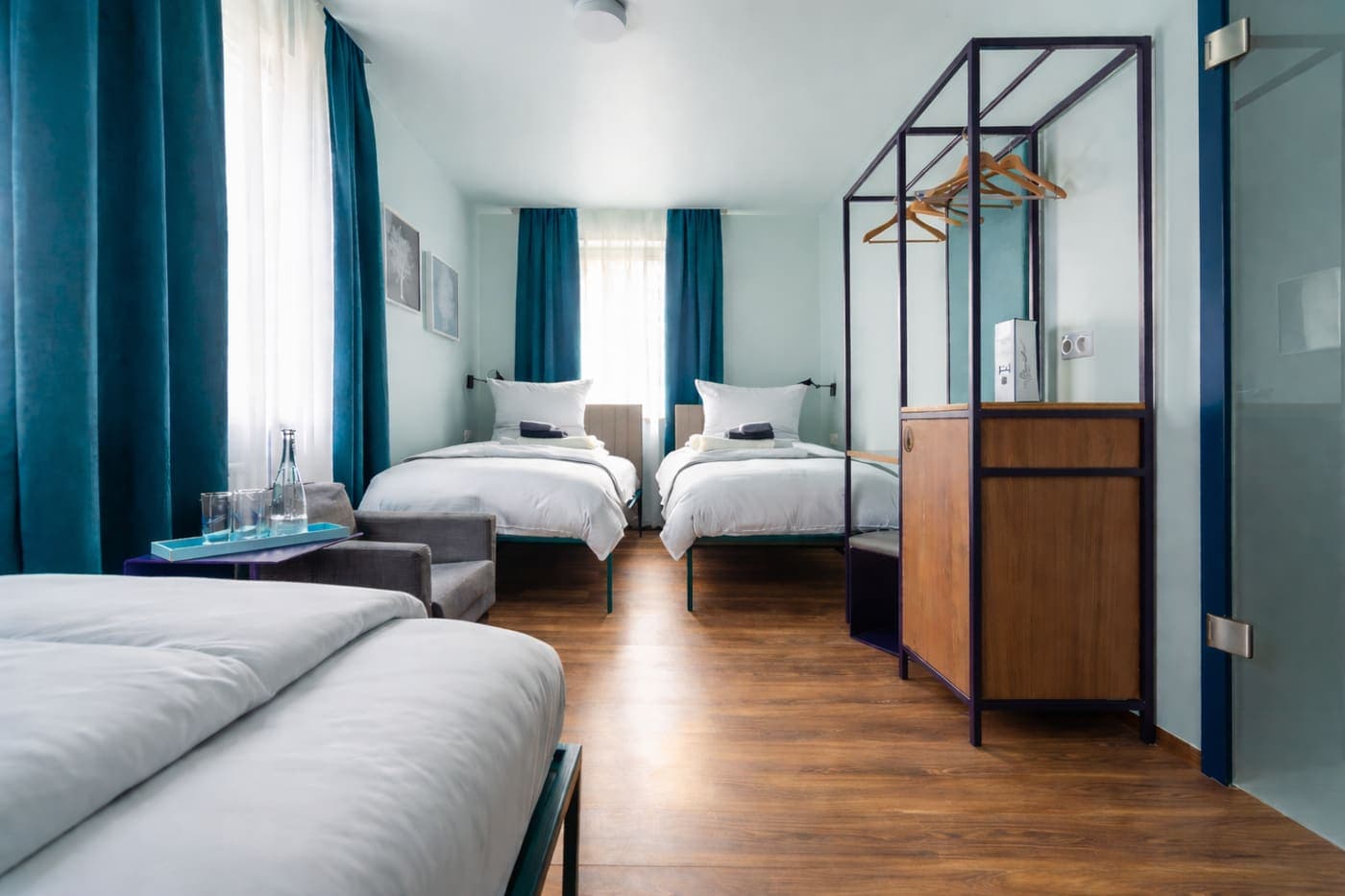 Classic 3-Bettzimmer im Das Schreder Hotel mit drei Betten und petrolfarbenen Vorhängen